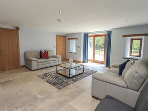 Ein geräumiges Wohnzimmer mit einer Couch, einem Glastisch und einer großen Schiebeglastür, die auf einen Balkon führt.