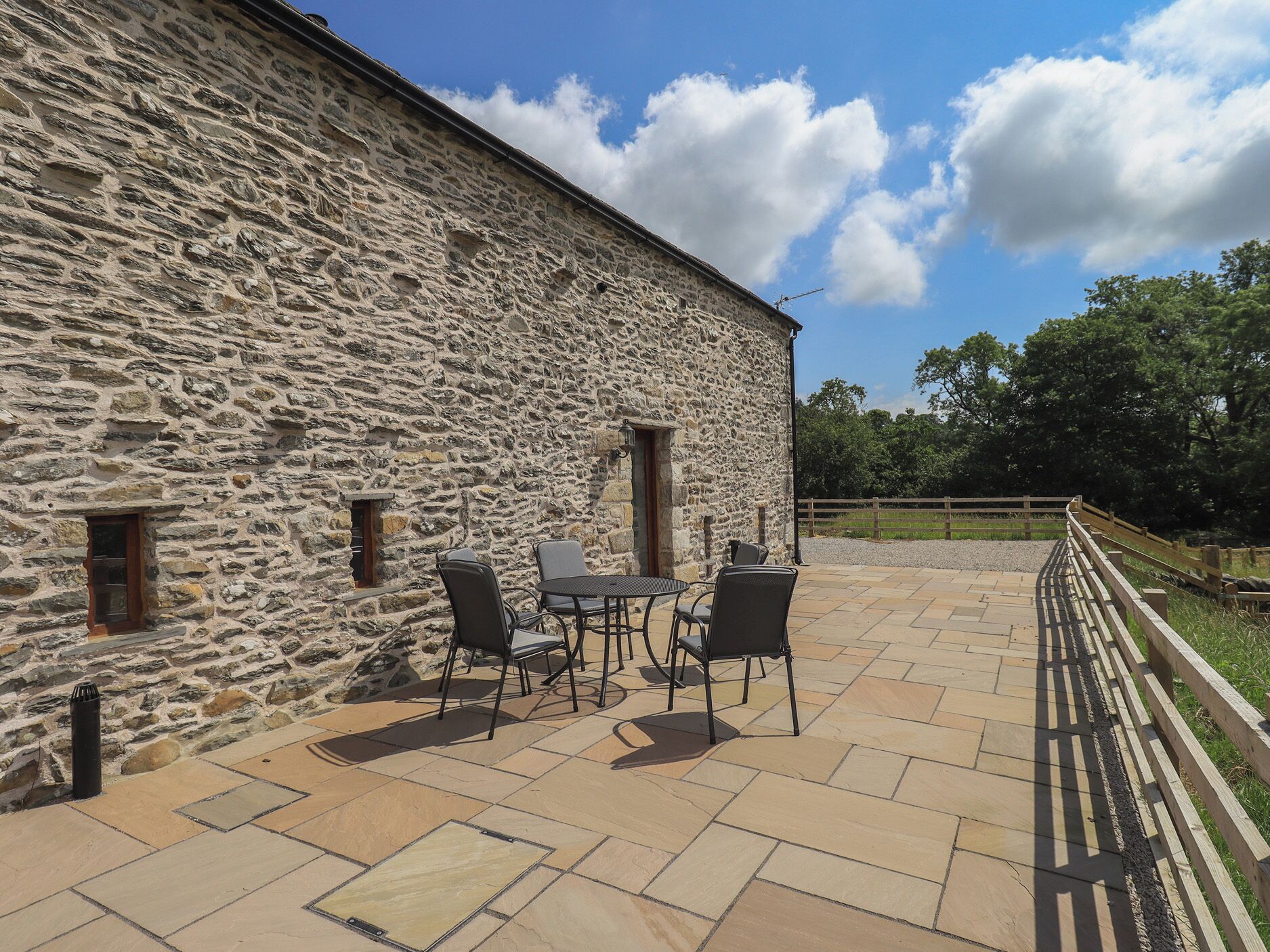 Un bâtiment en pierre doté d’un patio aménagé avec des espaces de détente en plein air.