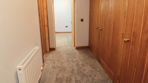 A hallway with a radiator, wooden wardrobe, and a door leading to another room. - Dam House Barn (Settle)