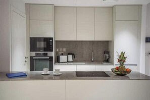 A modern kitchen with a microwave, toaster, sink, and a bowl of fruit on the counter. - Napa Horizon | Sea Front | Marina Tower 17th Floor (Famagusta)