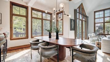 A spacious dining area with a large wooden table, four chairs, and a modern chandelier.