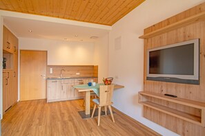 Una cucina moderna con mobili in legno, un tavolo da pranzo con sedie e un televisore montato a parete.