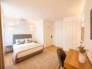 Ein modernes Hotelzimmer mit Bett, Nachttisch, Stuhl und einem Holztisch.