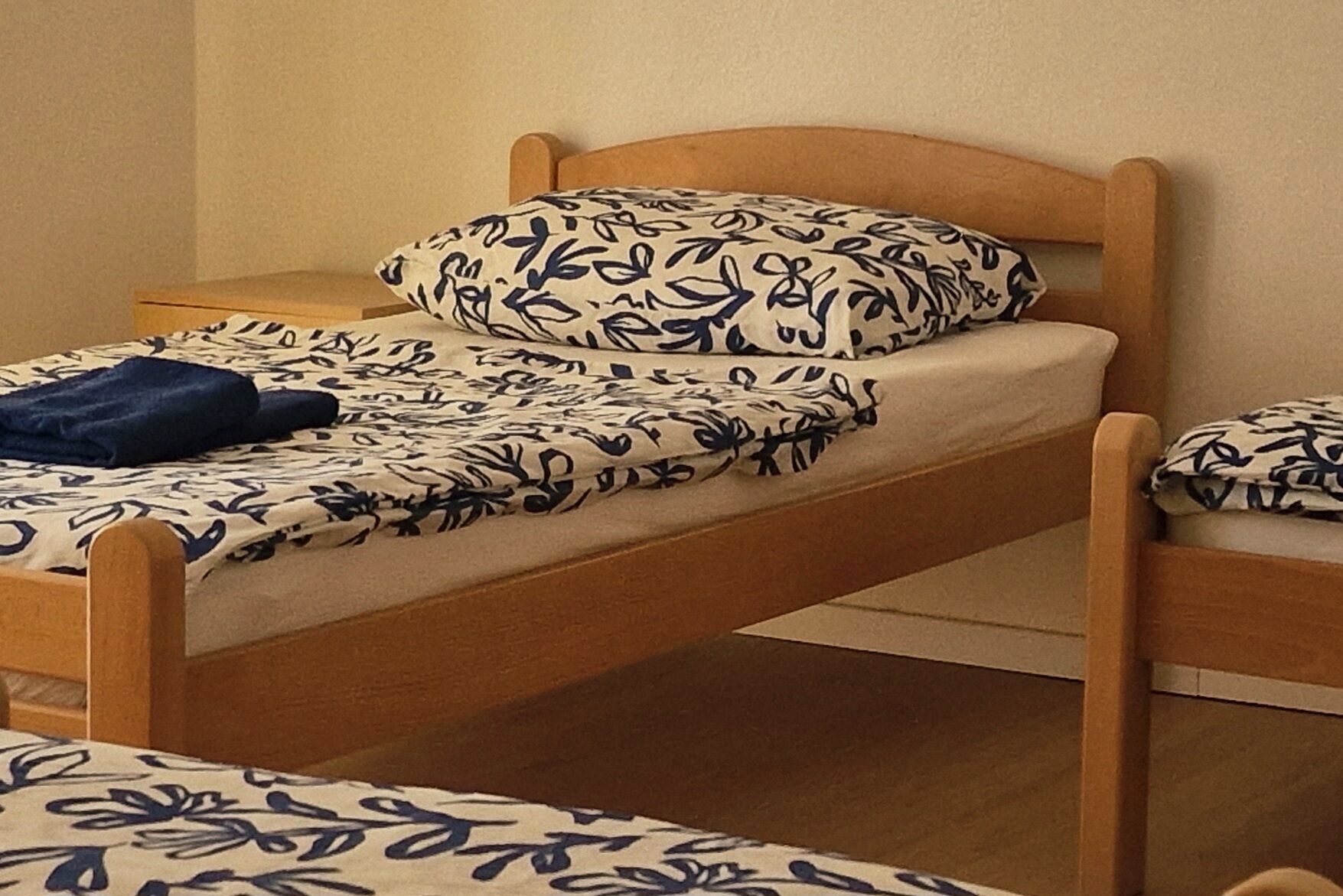 A single bed with a wooden frame and a floral-patterned bedspread.