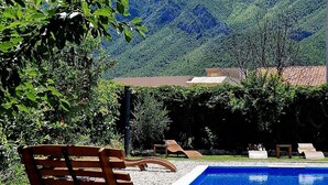 A pool with wooden loungers, a clear sky, and a mountainous backdrop. - A very nice and cozy vacation rental for 10 people, with a private pool and garden. (Mostar)