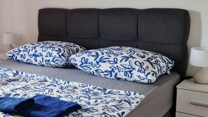 A bed with a grey headboard, blue and white patterned bedding, and a blue throw blanket. - A very nice and cozy vacation rental for 10 people, with a private pool and garden. (Mostar)