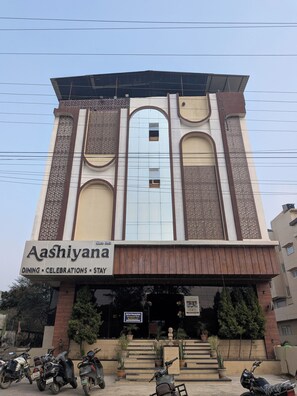Un bâtiment sur lequel on peut lire l’inscription « Aashiyana » et les mots « RESTAURATION – ÉVÉNEMENTS – HÉBERGEMENT ».