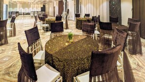 Un amplio salón de banquetes con mesas redondas, sillas y un piso de mármol.