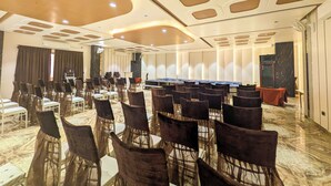 A conference room with rows of chairs, a stage, and a long table.