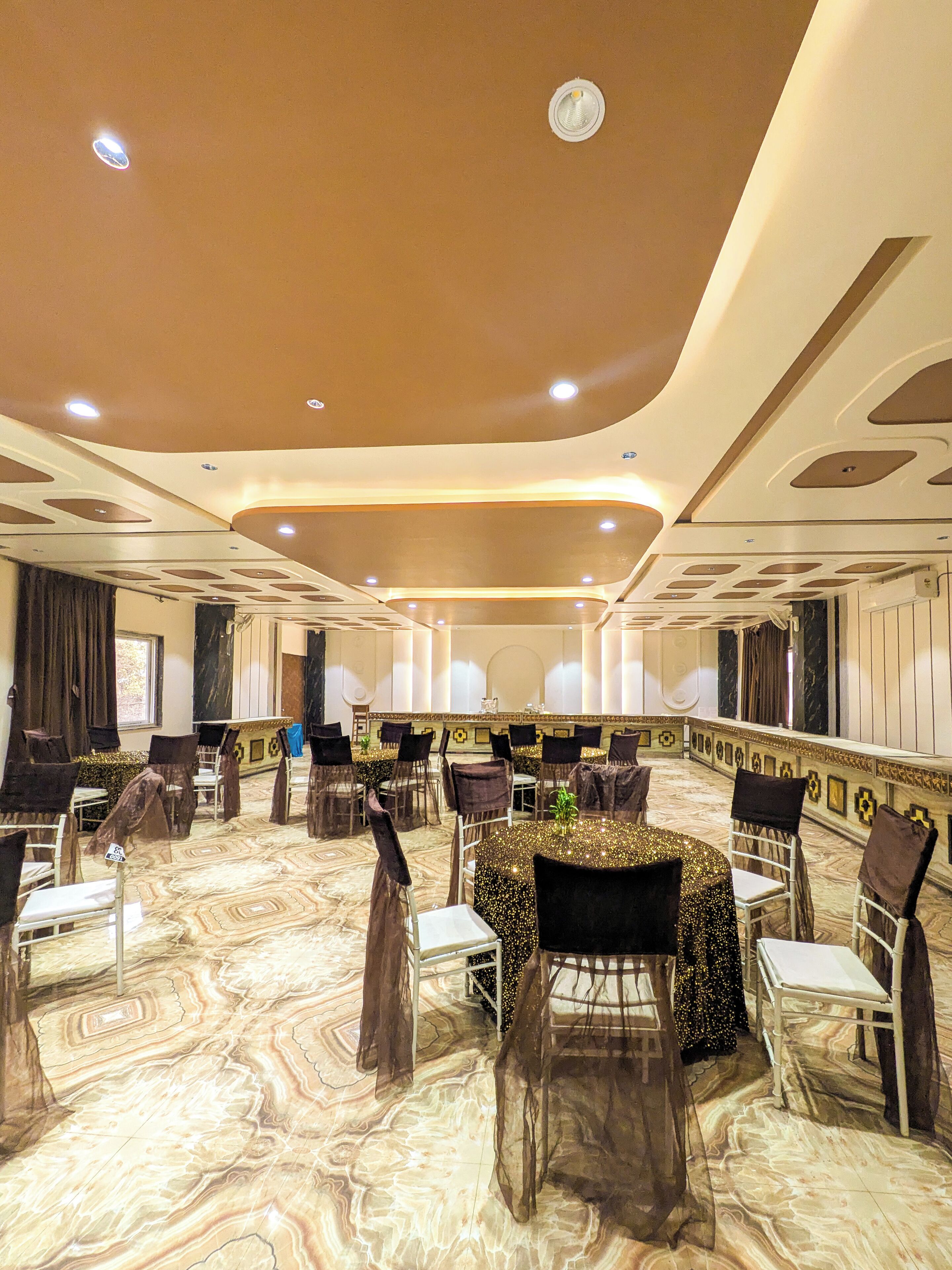 A banquet hall with round tables, chairs, and a marble floor.