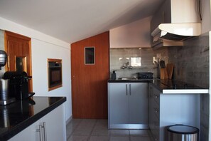 A modern kitchen with a built-in oven, a coffee machine, and a stainless steel sink. - Elysian Blue (Petalidi)