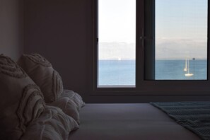 A bedroom with a large window, a bed, and a view of the sea. - Elysian Blue (Petalidi)