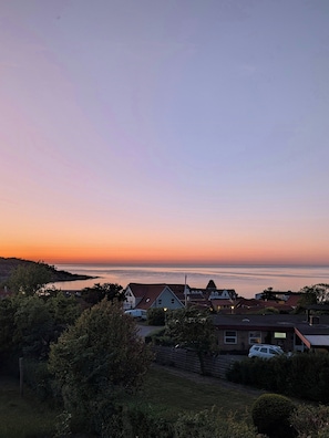 Eine Wohngegend an der Küste mit Häusern, blauem Himmel und Blick auf das Meer.