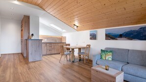Un interior moderno con techo de madera, zona de comedor, sofá y cocina al fondo.