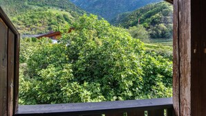 Vista desde un balcón de madera con vistas a un exuberante valle y montañas al fondo.