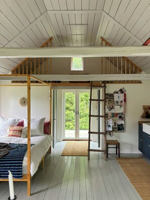 Ein Zimmer mit Hochlaggerl, einer Holzleiter, einem kleinen Fenster und einer Pinwand.