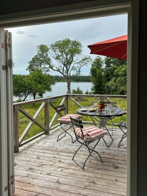 A wooden deck with a table and chairs, overlooking a lake. - Two houses in the middle of beautiful nature (Kronobergs län)