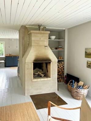 Ein Steinkamin mit Schornstein, ein gewebter Holzkorb und ein rustikaler Holzsessel.