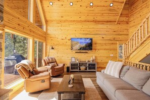 A wooden cabin interior with a large TV, leather sofas, and a fireplace. - Exceptional Views @ Stone Hearth Hideaway - Relax on the edge of the valley! (Duck Creek Village)