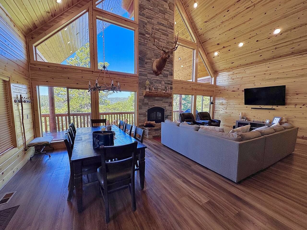 A spacious wooden cabin with a dining area, a fireplace, a large sofa, and a television.