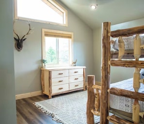 A room with a wooden dresser, a window with a view, a patterned rug, and a rustic wooden headboard. - Exceptional Views @ Stone Hearth Hideaway - Relax on the edge of the valley! (Duck Creek Village)