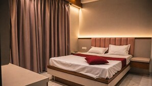 A modern bedroom with a bed, bedside tables, and a desk. - Hotel krushna palace lodge  (Wadwani)