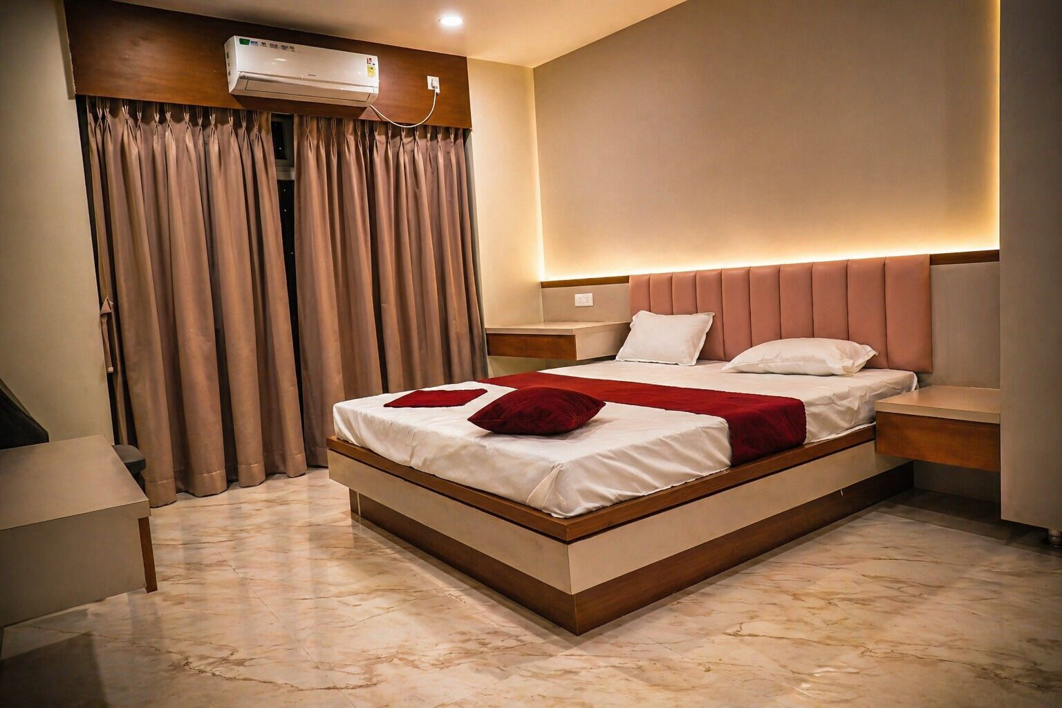 A modern hotel room with a large bed, a bedside table, a nightstand, an air conditioning unit, and a curtain.
