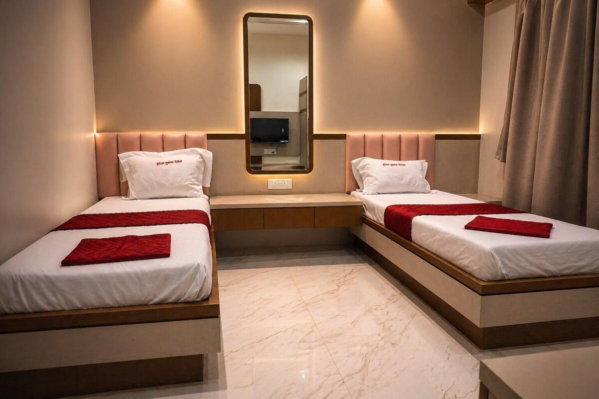 A hotel room with two beds, a mirror, a TV, and a small seating area.