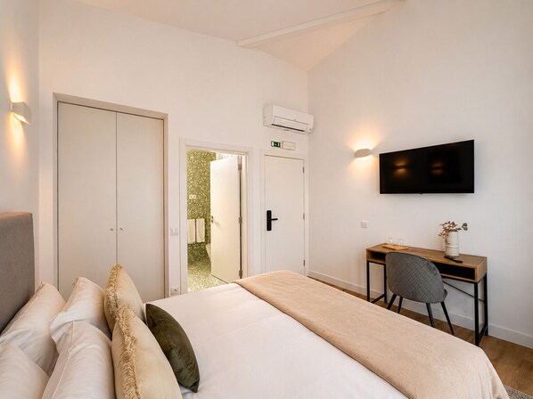 Ein Hotelzimmer mit Bett, Schreibtisch, Stuhl, Fernseher und Klimaanlage.