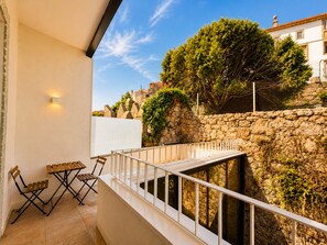 A balcony with a stone wall, a white railing, and a view of a tree and buildings. - Porto Ribeira Hotel - Double Room with Balcony (Porto)