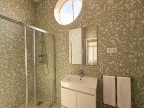 Ein Badezimmer mit Duschkabine aus Glas, einem Waschbecken mit Spiegel und einem Handtuchhalter.