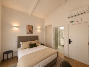 A bedroom with a bed, bedside tables, a wall-mounted air conditioner, and a door leading to a bathroom. - Porto Ribeira Hotel - Double Room with Balcony (Porto)