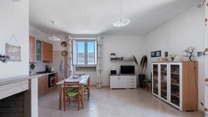Una cuina amb taula de dinar, cadires, armaris i un televisor.