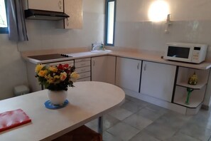 A kitchen with white cabinets, a microwave, a sink, and a vase with flowers on the counter. - Dream Vacations on the French Riviera: Apartment No. 2 (35 m²) + Private South-Facing Sun Deck (16 m²) (Châteauneuf-Grasse)