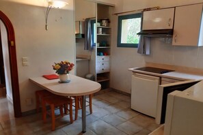 Eine kompakte Küche mit Esstisch, Stühlen, einem Backofen und einem Fenster.