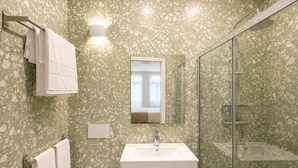 Une salle de bain avec une douche à parois de verre, un lavabo avec un miroir au-dessus et un porte-serviettes avec des serviettes.
