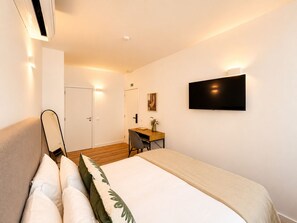 Ein Hotelzimmer mit Bett, Schreibtisch, Stuhl, Flachbildfernseher und Spiegel.