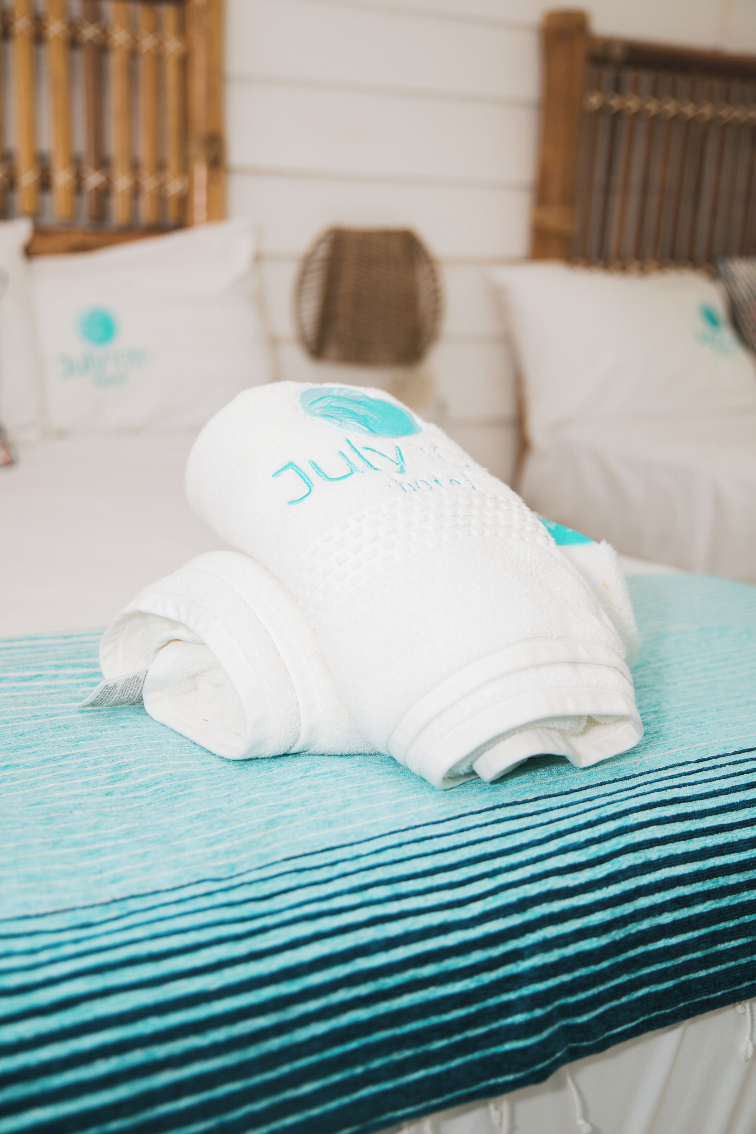 Una cama bien hecha con una toalla doblada y una almohada con un logotipo.