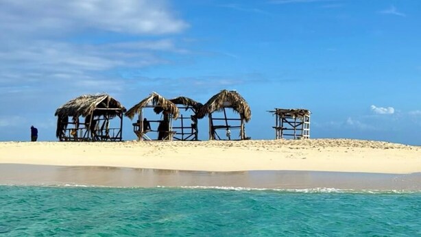 A beach with thatched-roof structures and a sandy shore. - July10th Hotel By Punta Rucia (Punta Rucia)