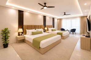 A hotel room with two beds, a ceiling fan, a TV, and a potted plant.