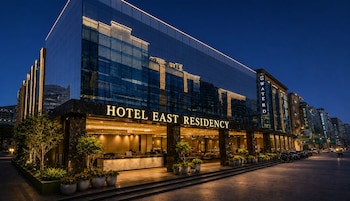 A modern hotel building with a glass facade, a reception area, and a well-lit entrance.