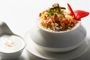 A bowl of biryani with a side of yogurt.