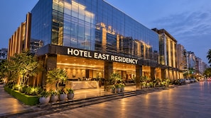 Um hotel moderno com fachada de vidro, entrada bem iluminada e área de recepção visível.