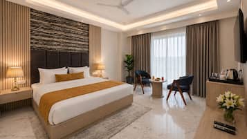 A modern hotel room with a large bed, a desk with a TV, a seating area, and a ceiling fan.