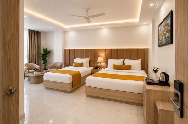 A hotel room with two beds, a ceiling fan, a bedside table with a lamp, a coffee maker, and a painting on the wall.