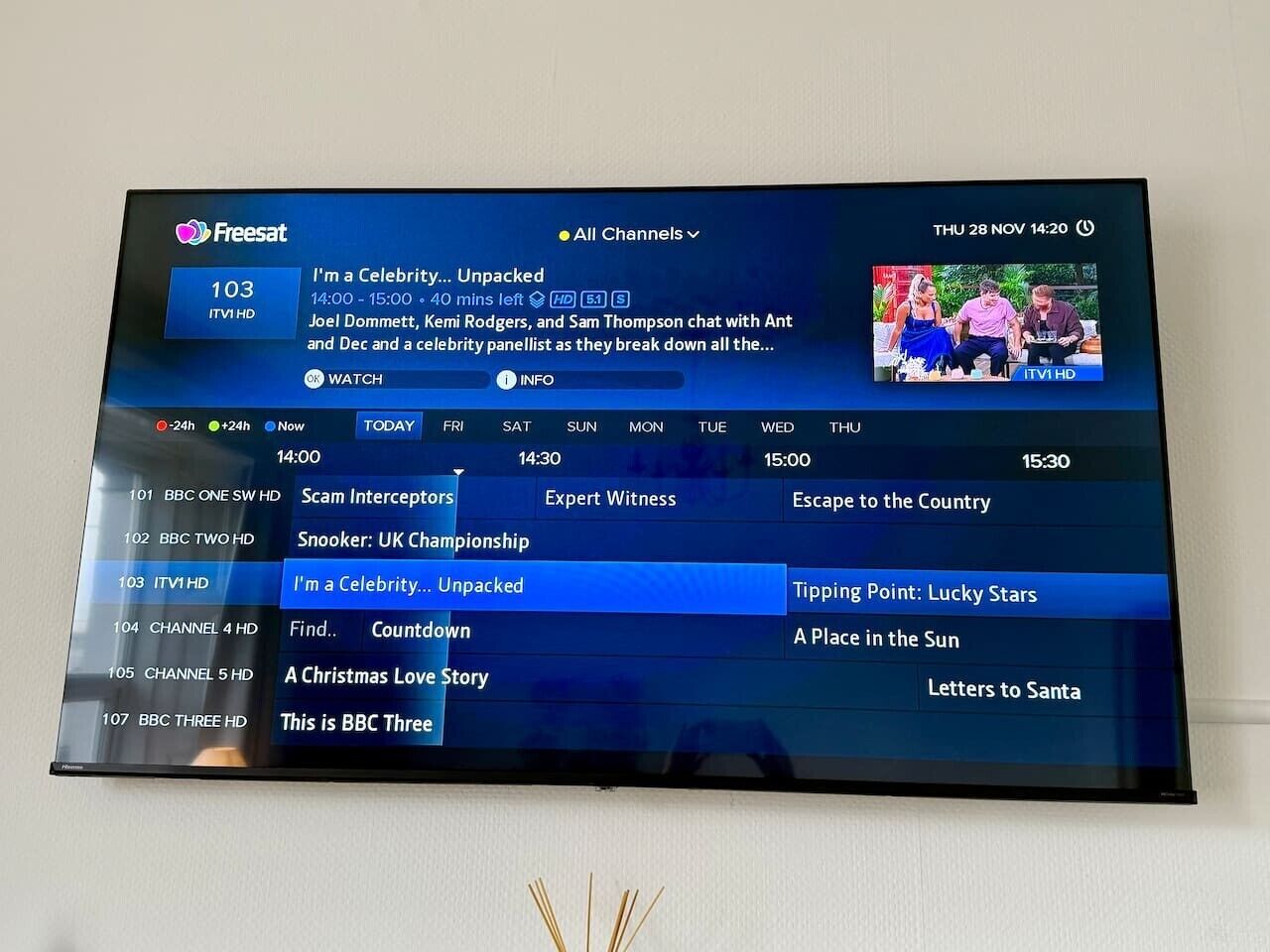 Un écran de télévision affiche un guide de programmes télévisés, avec une liste des différentes chaînes et émissions.