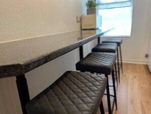 Eine Reihe von Barhocker mit einer gesteppten Gestaltung, einer Arbeitsplatte und einem Fenster mit Tageslicht.