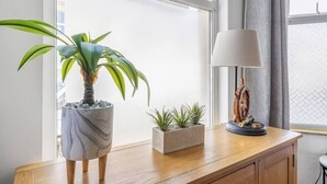 Ett skrivbord i trä med en krukväxt, en liten terrakottakruka med suckulenter och en skrivbordslampa i vintage-stil.