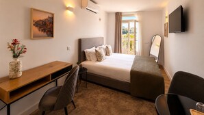 A hotel room with a bed, desk, chair, TV, and a painting. - Porto Ribeira Hotel - Superior Double Room (Porto)