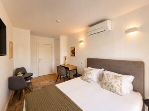Ein Hotelzimmer mit einem Bett, einem Schreibtisch, einem Stuhl, einer Klimaanlage und einer Wandleuchte.